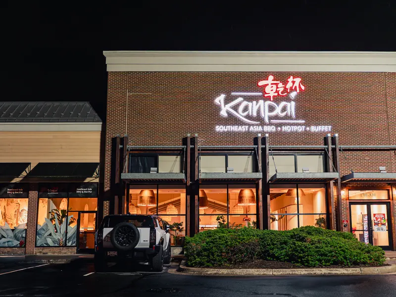 Kanpai's brick storefront at night, its lit sign above glowing windows with rattan lamps inside